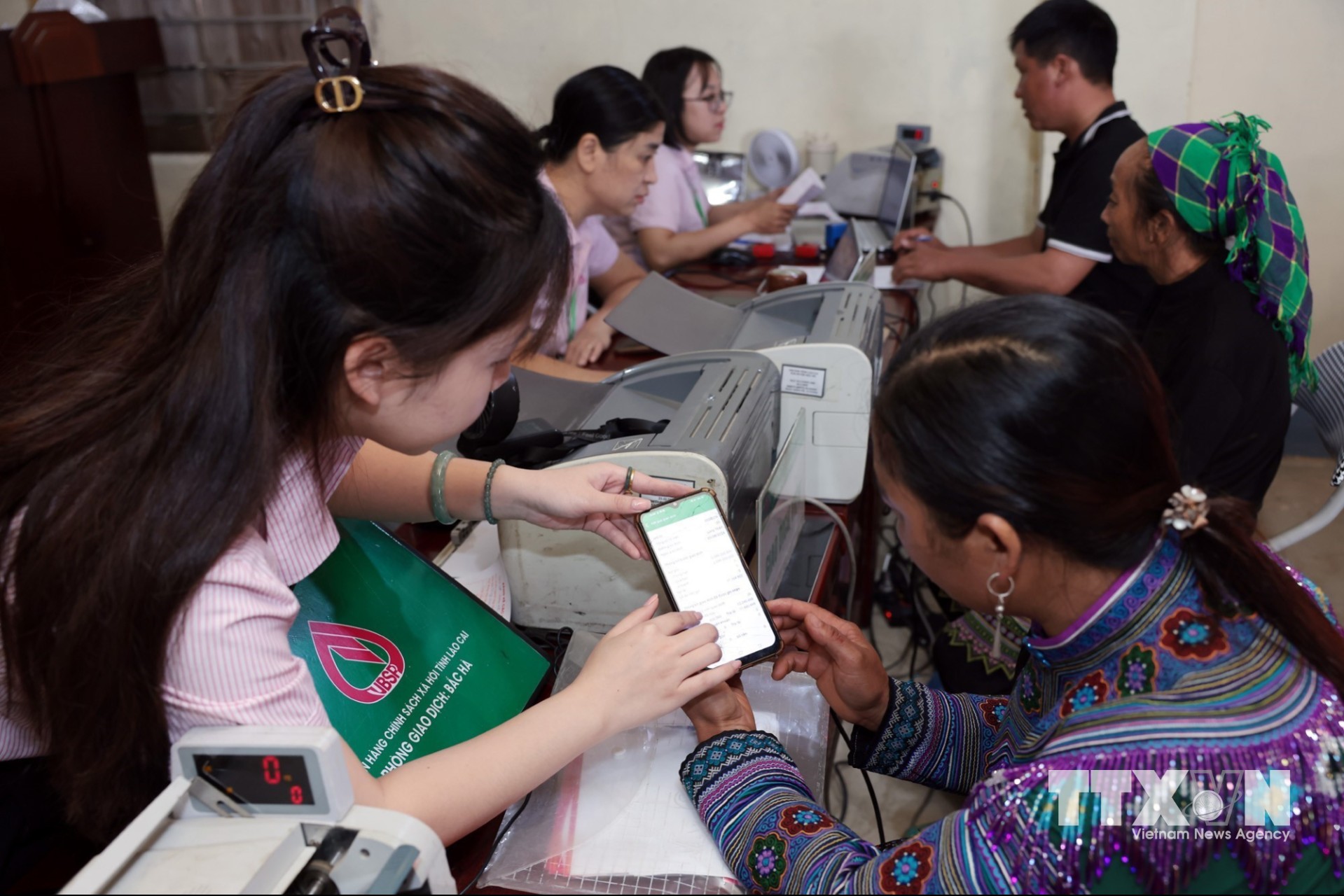 Tổ trưởng Tổ Tiết kiệm và vay vốn sử dụng phần mềm trên điện thoại để giao dịch tại điểm giao dịch xã Lùng Thần, Lào Cai. (Ảnh: Trần Việt/TTXVN)